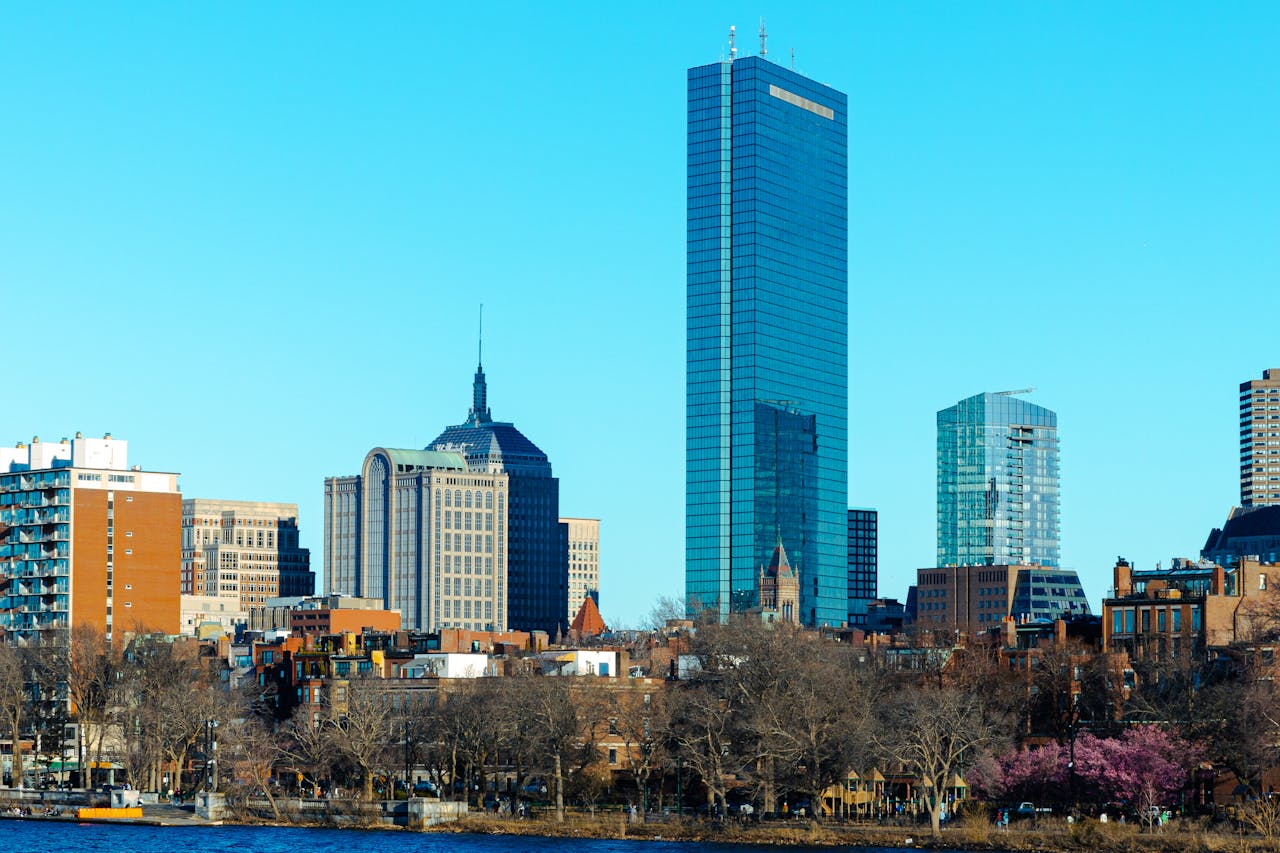 Boston skyline featuring the John Hancock Tower reflected in the Charles River on a clear winter day.